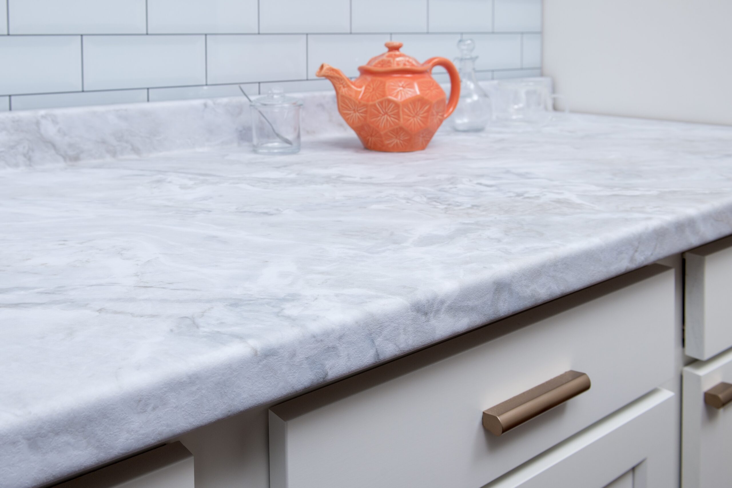 HPL Stone Series_56 A stone look countertop with an orange tea kettle sitting on top.