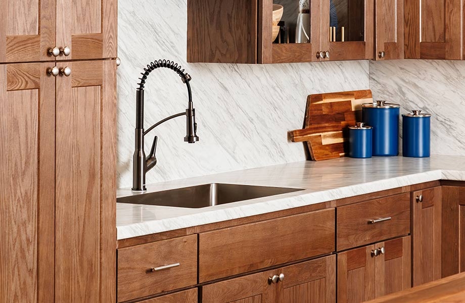 Kitchen with wood cabinets, island with bar stools, shelves and marbled backsplash