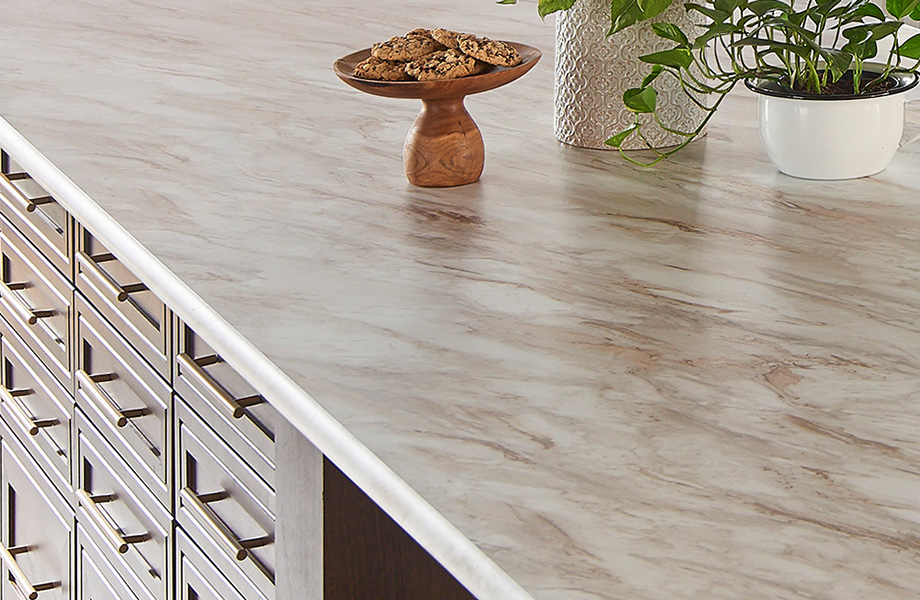 Cream and brown veined Drama Marble Wilsonart laminate kitchen island with wood cabinets, plants and plate of cookies