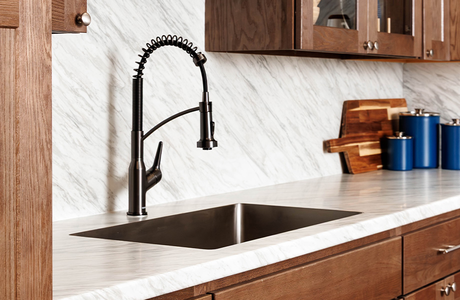 Stainless steel kitchen sink with commercial-style faucet and cutting board set against Manhattan Marble 180fx Laminate countertops and backsplash